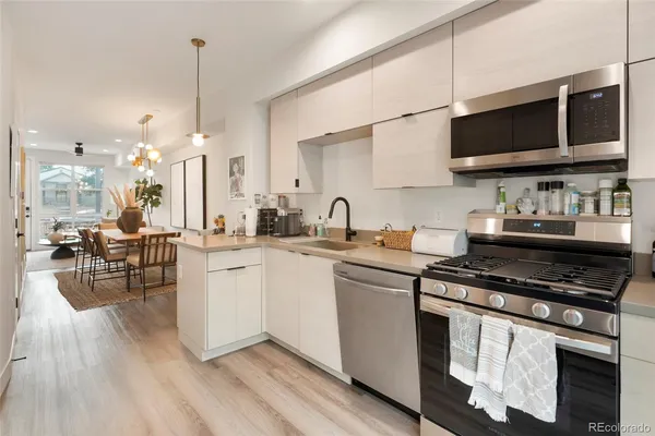 a kitchen with stainless steel appliances a stove a sink dishwasher a microwave oven and a dining table with wooden floor