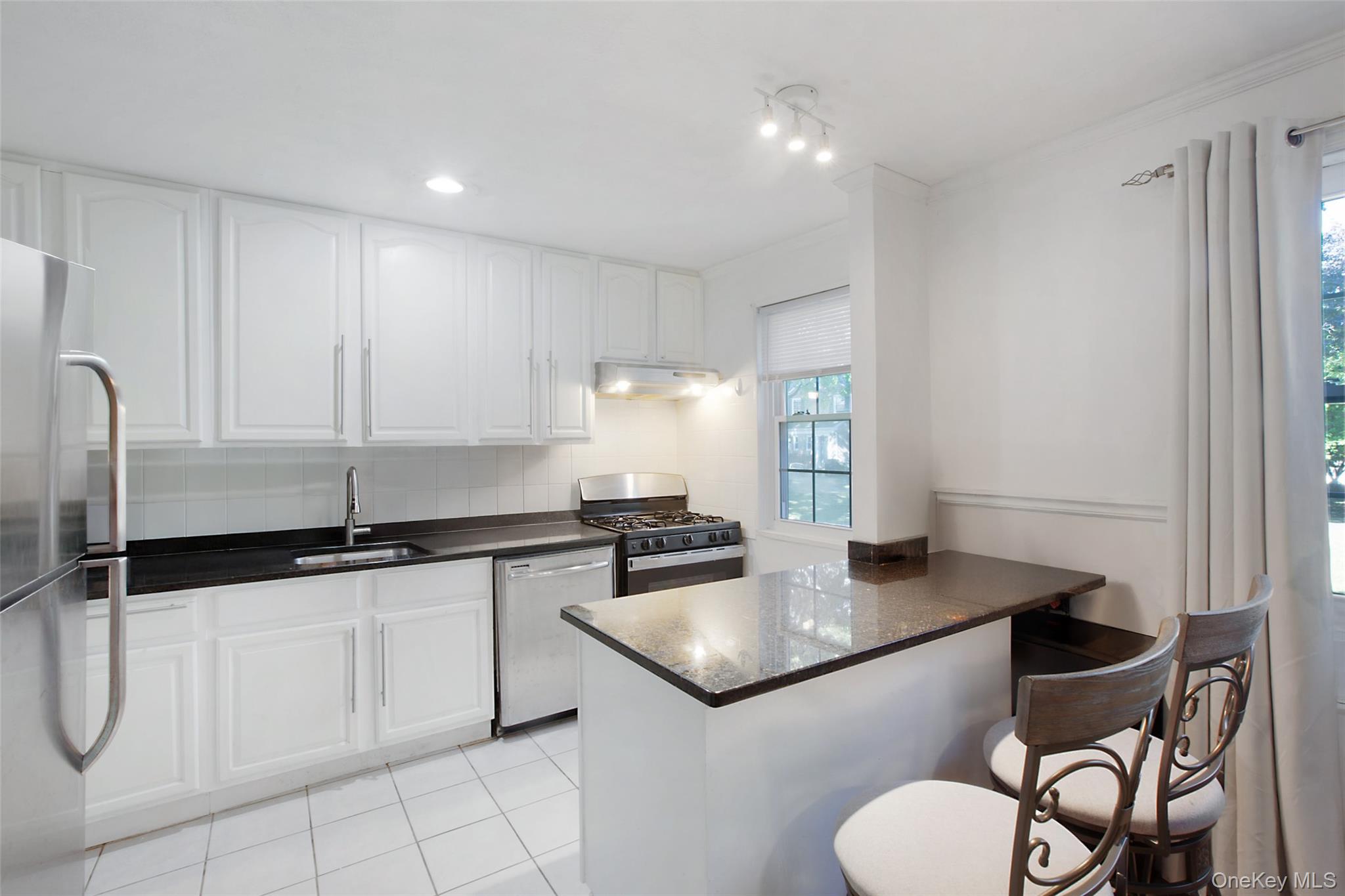 a kitchen with granite countertop a sink a stove cabinets and counter space