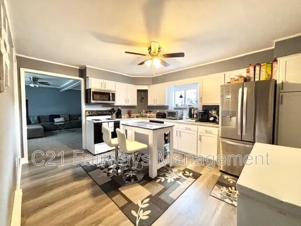 a kitchen with stainless steel appliances kitchen island granite countertop a refrigerator stove top oven and sink