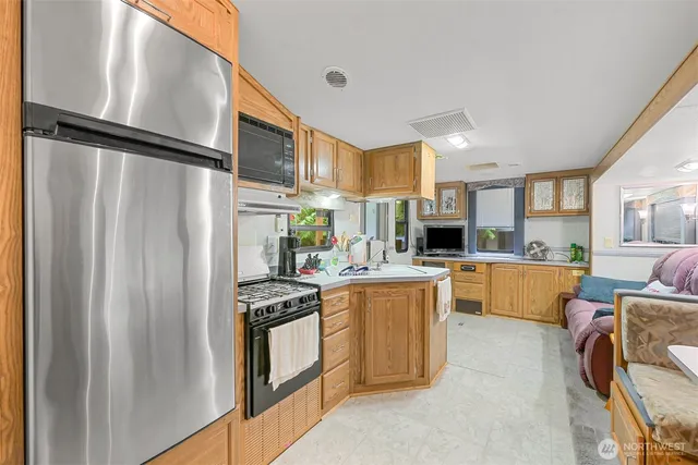 a kitchen with stainless steel appliances granite countertop a refrigerator a stove and a sink with wooden floor