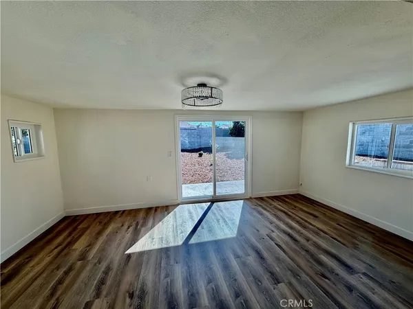 a view of an empty room with window and wooden floor