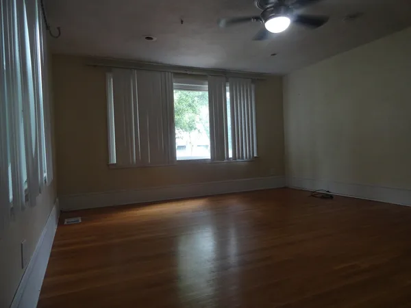 an empty room with wooden floor and windows