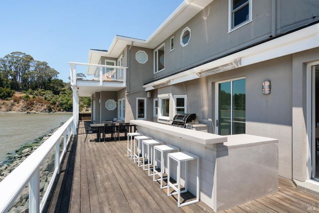 a view of a patio with couches table and chairs with wooden floor and fence