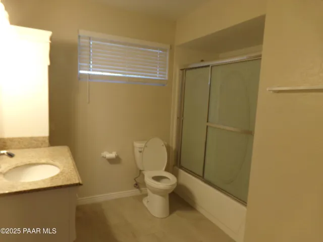a bathroom with a granite countertop toilet and a sink