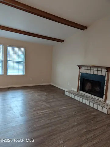 an empty room with wooden floor fireplace and windows