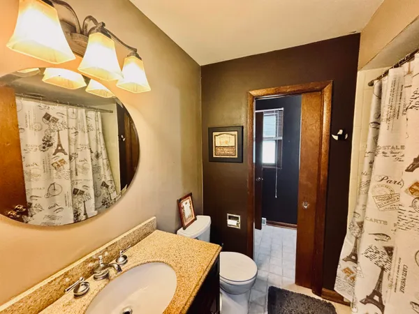 a bathroom with a granite countertop toilet sink and mirror