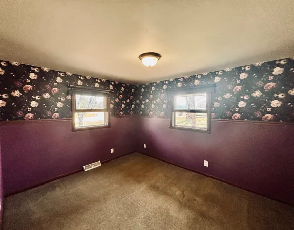 an empty room with windows and ceiling fan