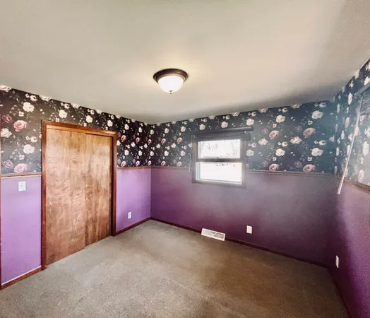 an empty room with a large window and chandelier fan
