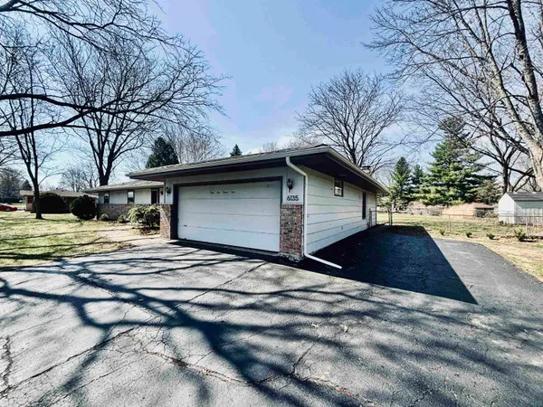 a backyard of a house with large trees and outdoor seating