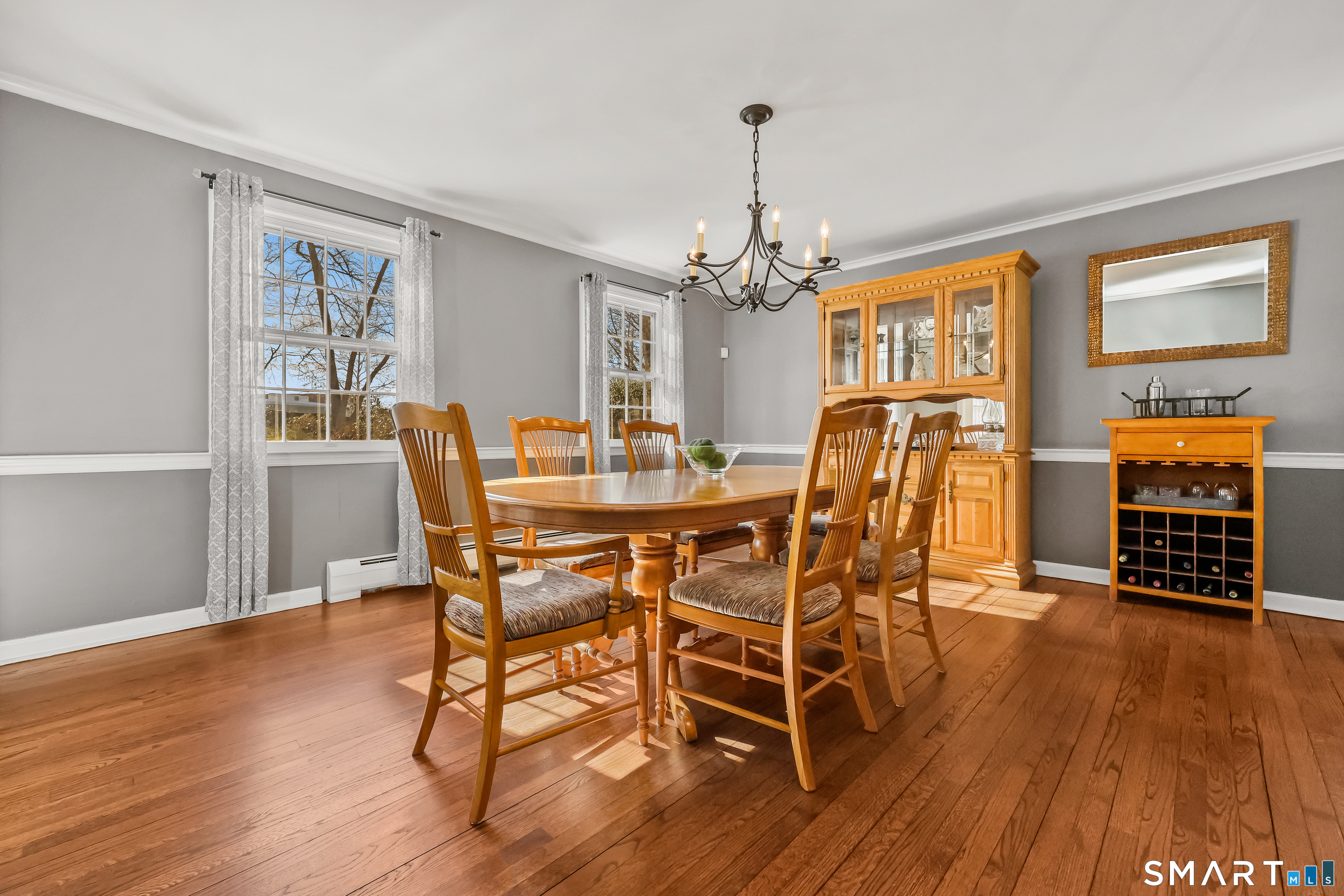 610 Unquowa Road Fairfield, CT 06824 - Photo 24 of 43 a dining room with wooden floor a chandelier a wooden table and chairs