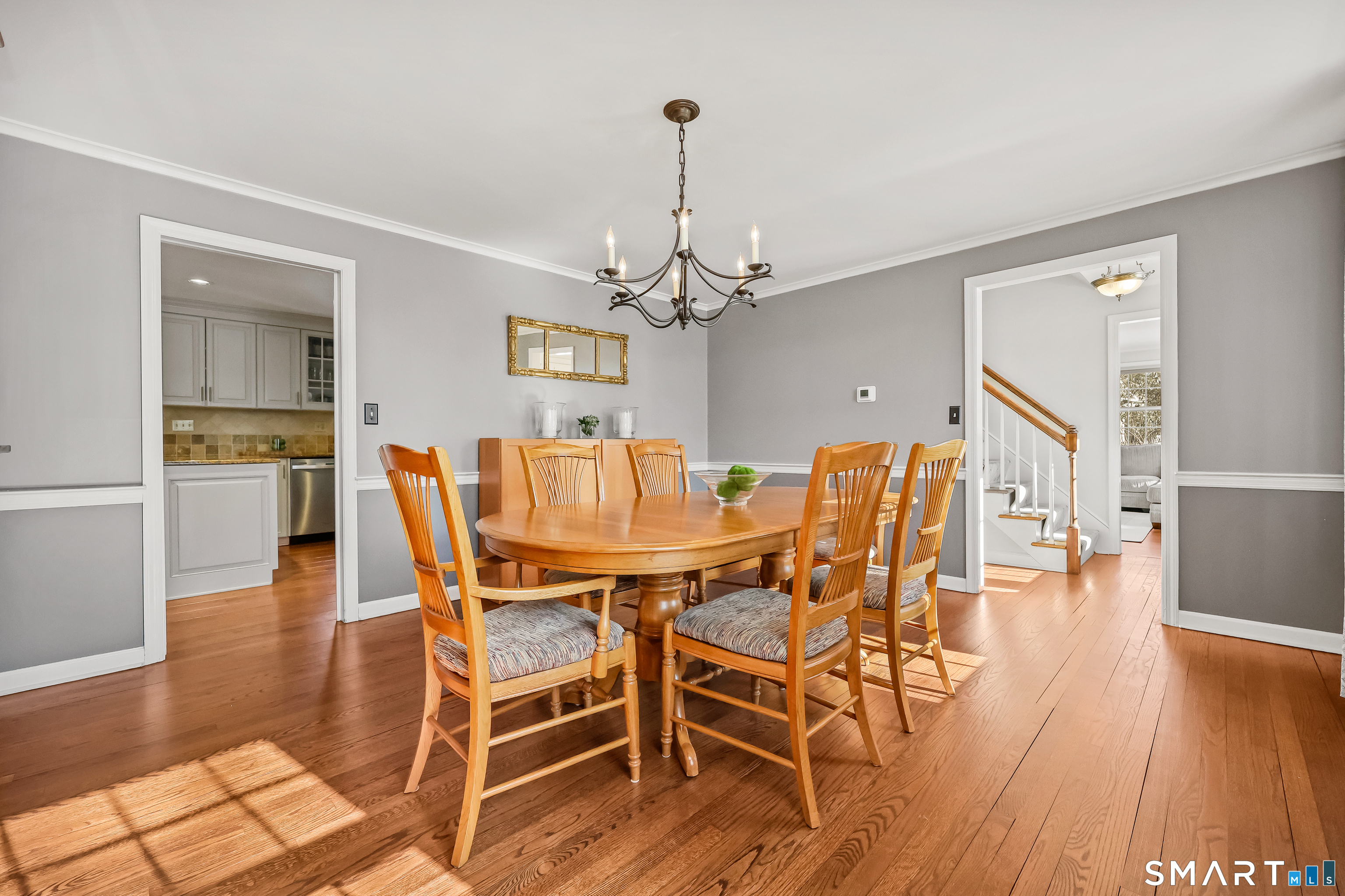 610 Unquowa Road Fairfield, CT 06824 - Photo 25 of 43 a dining room with wooden floor a chandelier a glass table and chairs