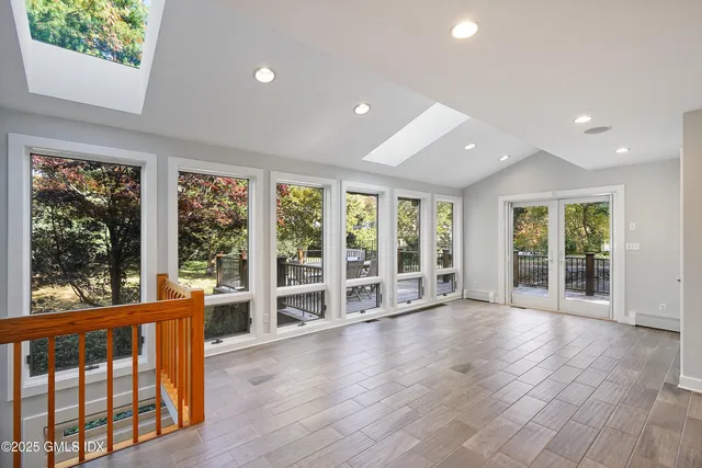 an empty room with wooden floor and large windows