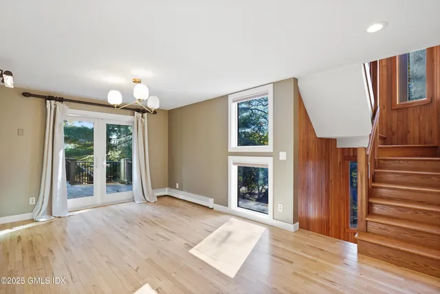 a view of an empty room with wooden floor fireplace and a window