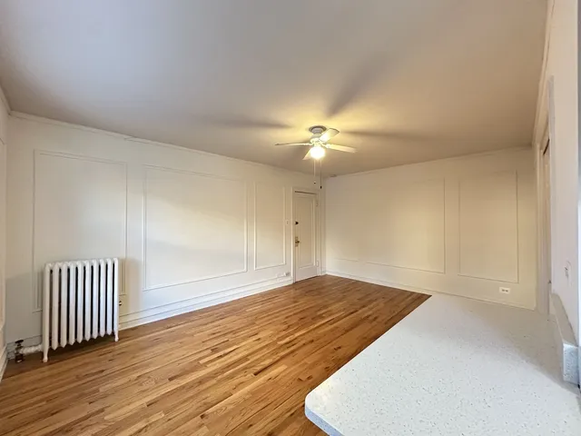 an empty room with wooden floor and chandelier fan