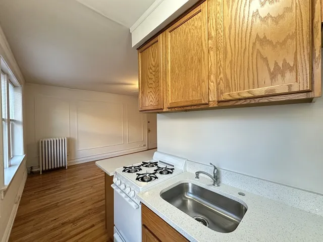a kitchen with granite countertop a sink a stove and wooden floor