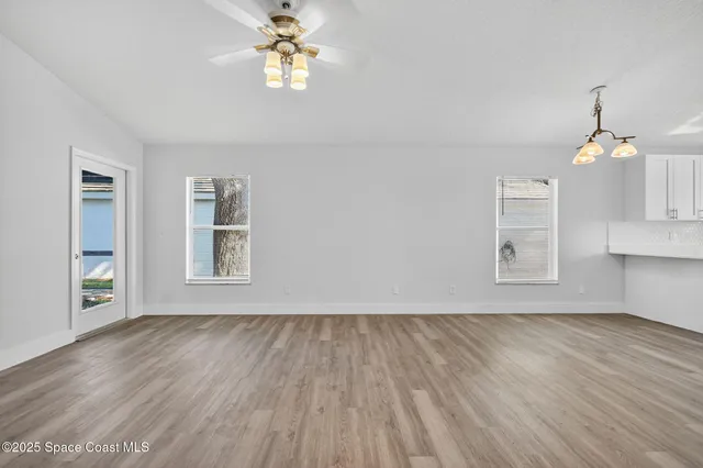 a view of empty room with wooden floor and fan