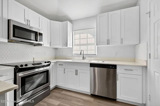 a kitchen with white cabinets and stainless steel appliances