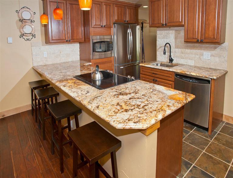 4192 Spruce Way, Unit 204A Vail, CO 81657 - Photo 9 of 21 a kitchen with stainless steel appliances kitchen island a table chairs in it and wooden floors