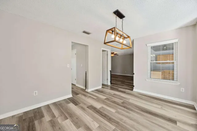 an empty room with wooden floor cabinet and windows