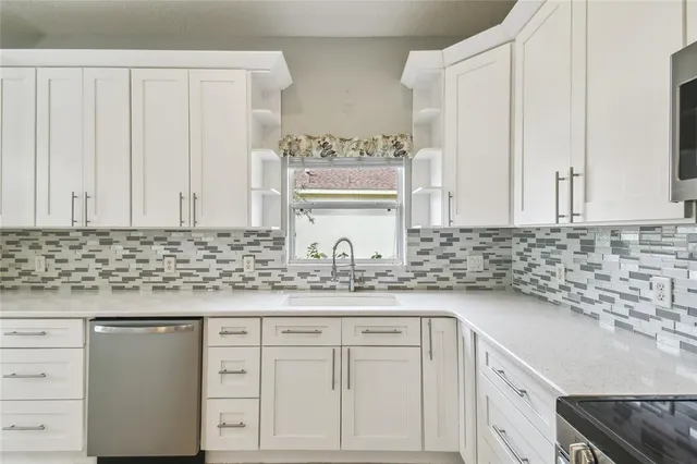 a kitchen with granite countertop white cabinets and a sink