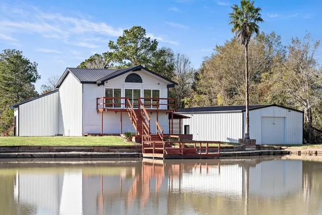 a small white house with a white roof and lake view