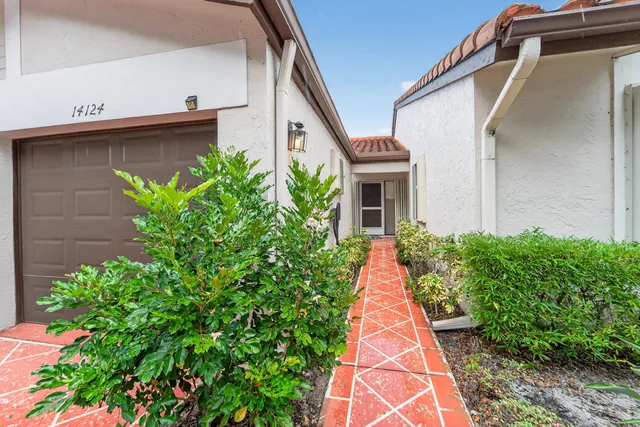 a front view of a house with a yard and potted plants