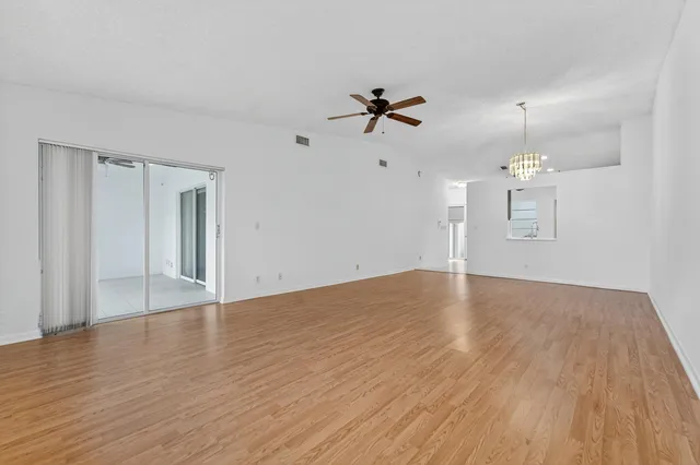 a view of empty room with wooden floor and ceiling fan