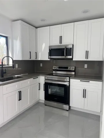 a kitchen with granite countertop white cabinets and stainless steel appliances