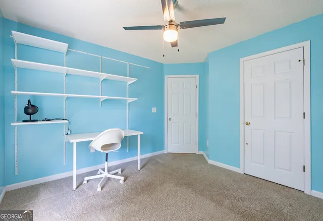 an empty room with windows and ceiling fan