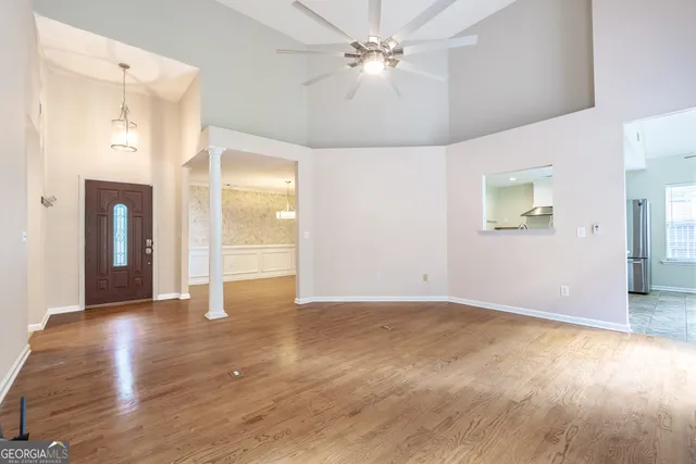 a view of an empty room with window and wooden floor