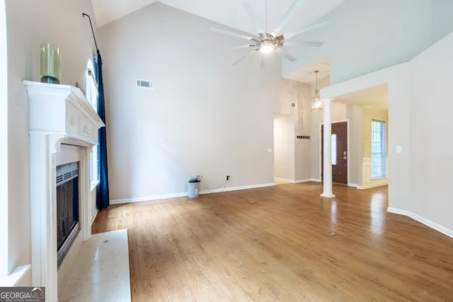 a view of a livingroom with a fireplace a ceiling fan and front door