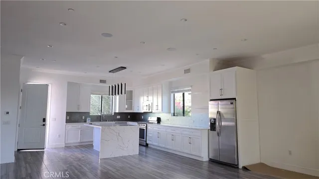 a large white kitchen with white cabinets and wooden floor