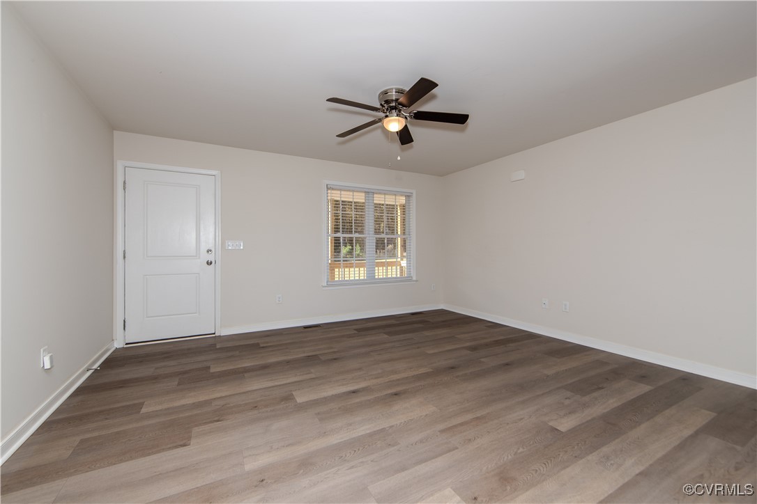 14671 Baltimore Road Dewitt, VA 23840 - Photo 7 of 27 an empty room with wooden floor ceiling fan and windows
