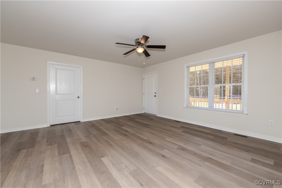 14671 Baltimore Road Dewitt, VA 23840 - Photo 9 of 27 an empty room with wooden floor ceiling fan and windows
