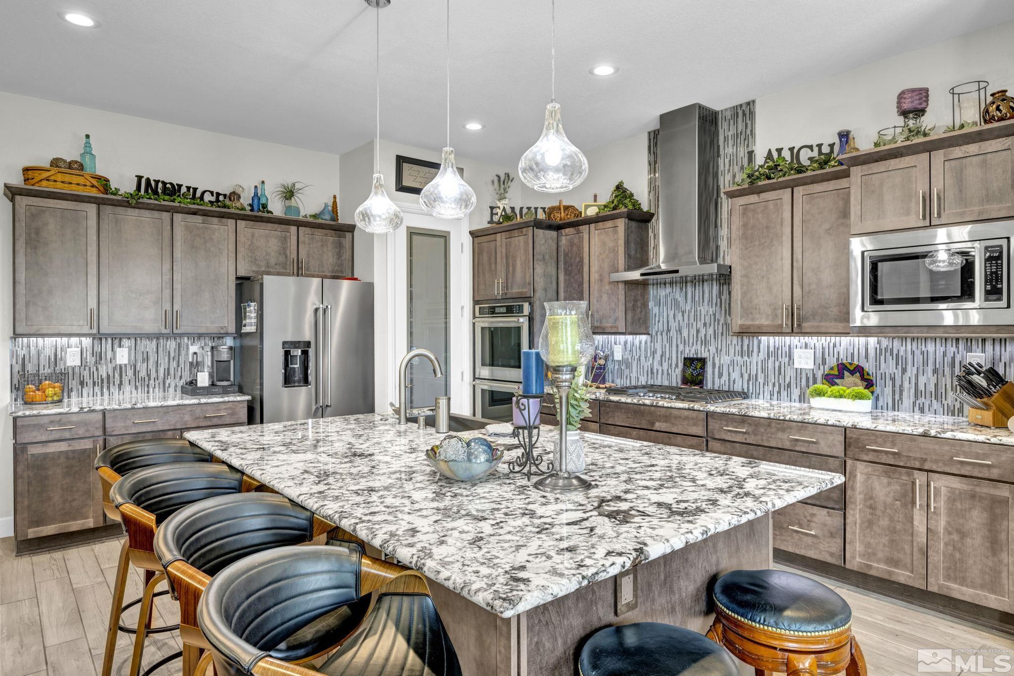 a kitchen with stainless steel appliances kitchen island granite countertop a table chairs and a wooden cabinets