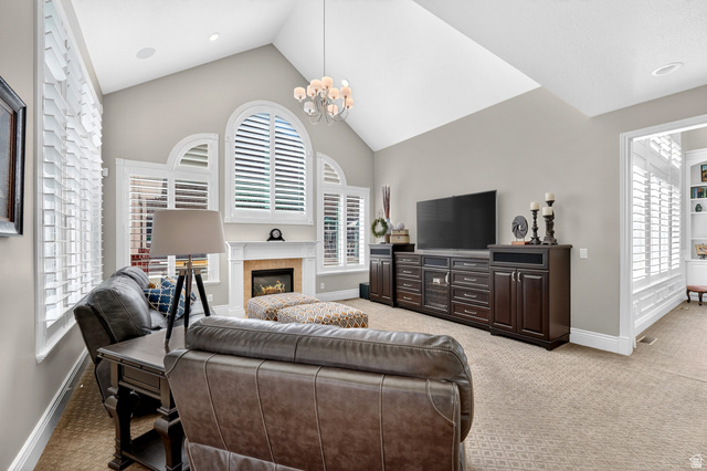 714 Draper Heights Way Draper, UT 84020 - Photo 35 of 88 Living area featuring light carpet, a high ceiling, a fireplace, and hanging lights