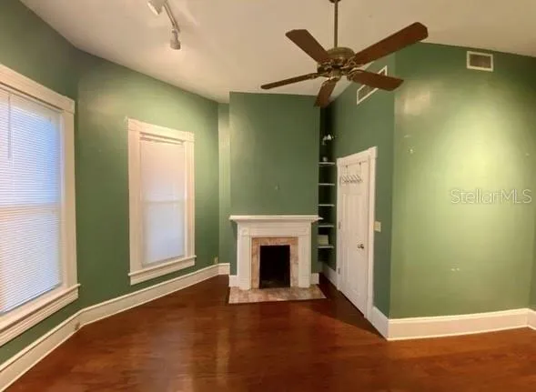 an empty room with windows and fan