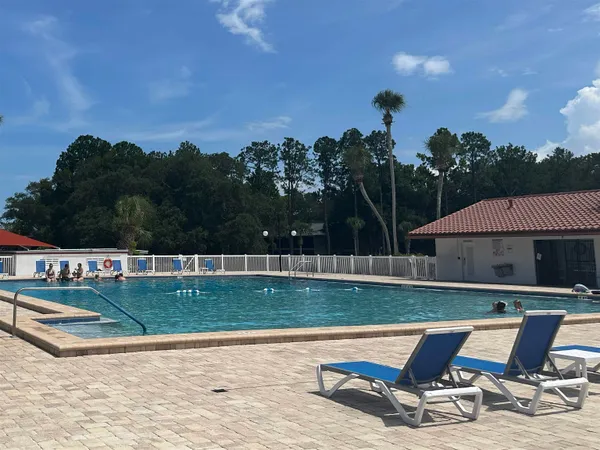 a view of a swimming pool with lawn chairs under an umbrella