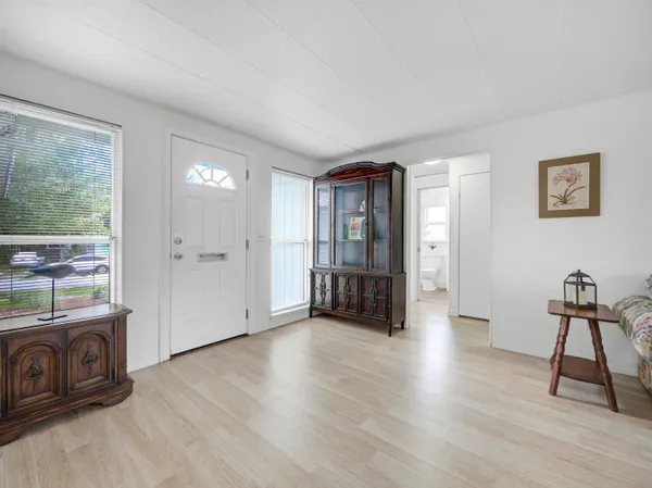 a view of an empty room with window and hardwood floor