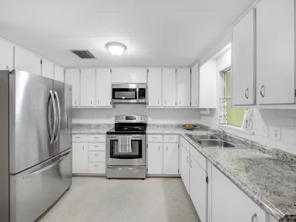 a kitchen with stainless steel appliances granite countertop a refrigerator stove microwave and sink