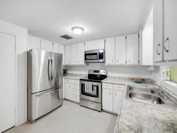 a kitchen with stainless steel appliances granite countertop a refrigerator sink stove and microwave
