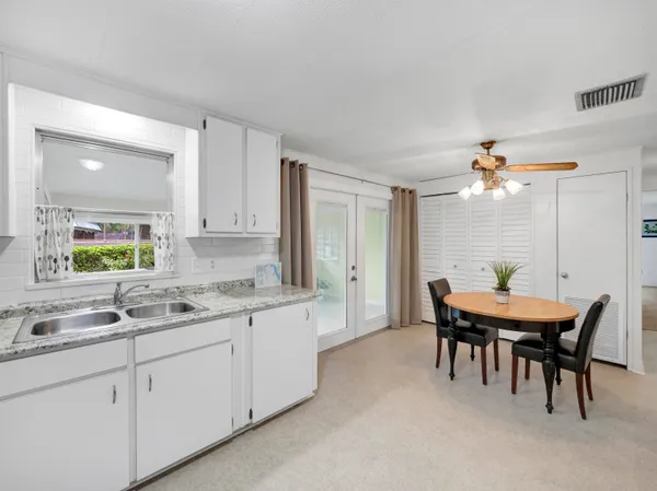 a kitchen with a dining table chairs and white appliances