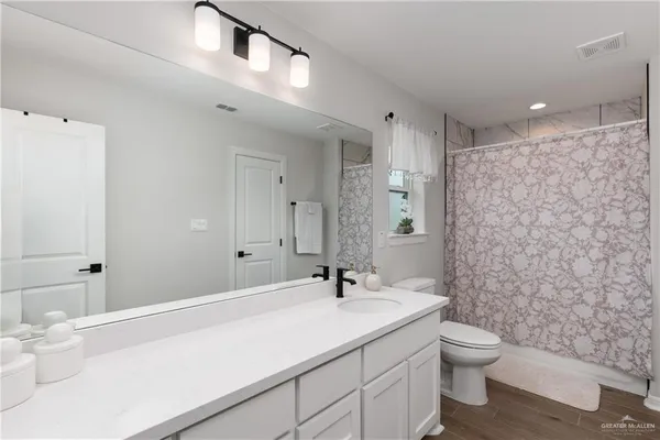 a bathroom with a granite countertop sink a toilet and a shower