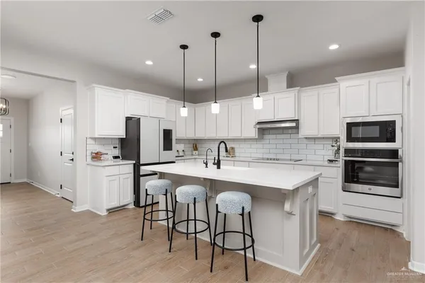 a kitchen with stainless steel appliances kitchen island granite countertop a stove a sink and a refrigerator