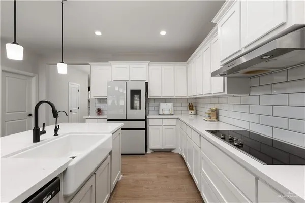 a kitchen with a sink white cabinets and stainless steel appliances