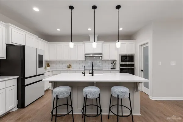 a kitchen with stainless steel appliances kitchen island granite countertop a dining table chairs refrigerator and sink
