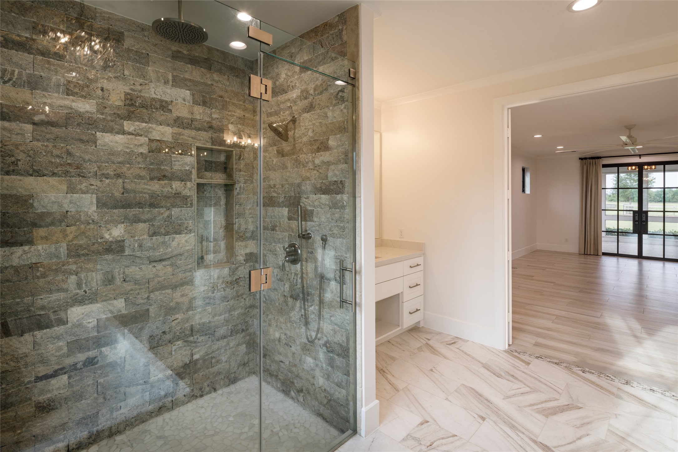 24118 Margerstadt Road Hockley, TX 77447 - Photo 24 of 46 The walk-in shower combines oversized proportions, natural stone finishes, and frameless glass within a clean and open layout. Thoughtful scale and soft natural light continue the refined feel carried throughout the primary suite.