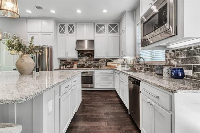 a kitchen with kitchen island white cabinets stainless steel appliances a sink and a refrigerator