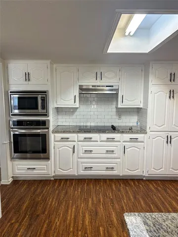 a kitchen with granite countertop white cabinets and stainless steel appliances