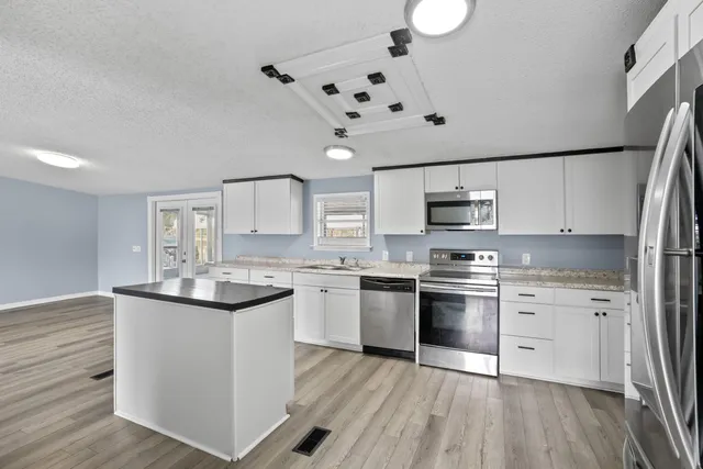 a kitchen with stainless steel appliances granite countertop a sink stove and refrigerator